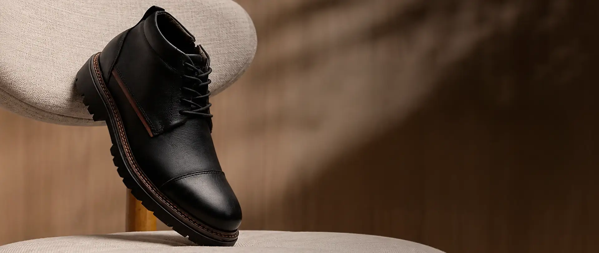 Bota de couro preta da Ferracini apoiada em uma poltrona
